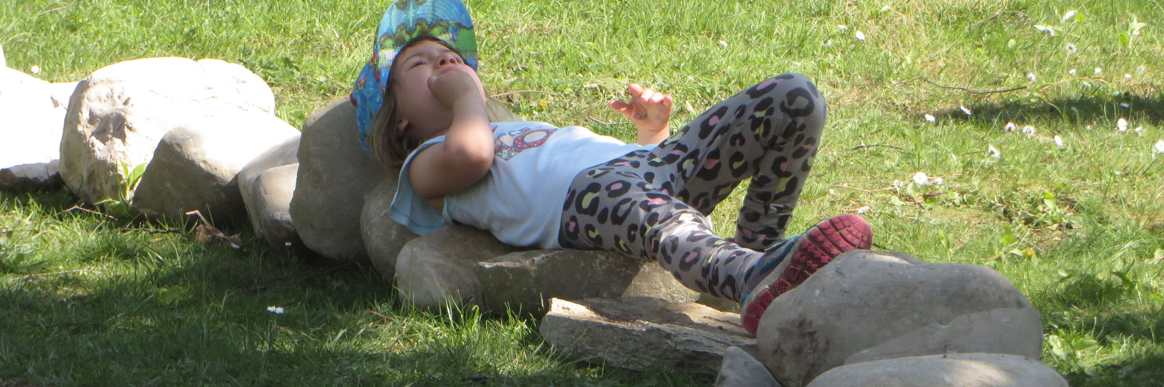 Denkpause: Kind ruht sich auf Steinen aus.